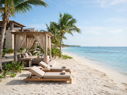 Exclusive private beachfront cabana with linen daybeds, teak lounger chairs on powdery white sand, swaying coconut palms and crystal turquoise sea